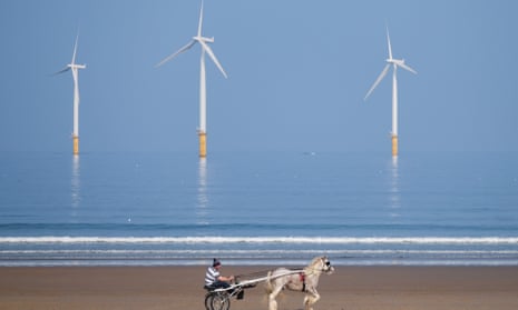 A man rides his horse and trap along the beach in front of the EDF energy windfarm at Redcar, northern England. 