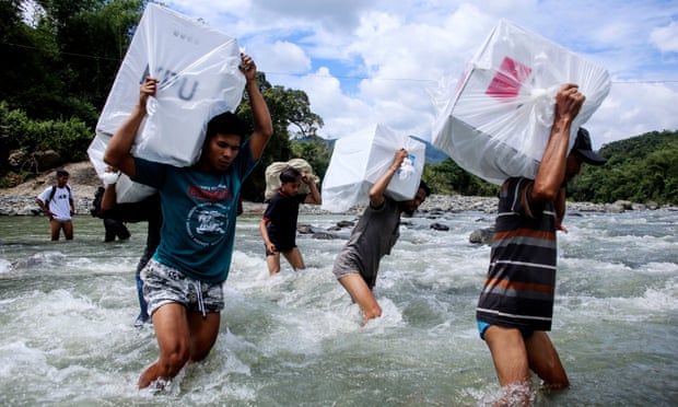 Indonesian election workers carry ballot boxes as they cross a river to deliver them to remote villages in Maros, South Sulawesi