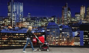 A woman pushes a pram past a banner advertising new ‘luxury’ apartments in the East End.