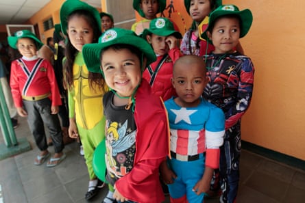 Children dressed in superhero costumes with green hats pose for  the camera.