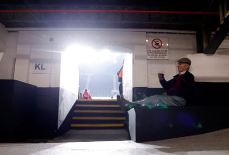 A fan holds a drink before the match between Fulham and Brentford at Craven Cottage