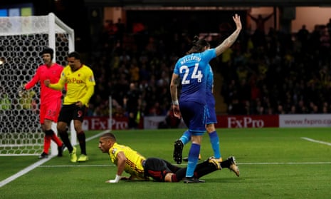Arsenal’s Héctor Bellerín celebrates the award of a penalty awarded to the prone Richarlison, as Troy Deeney celebrates in front of a disconsolate Petr Cech