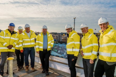 Seven men in hard hats and hi-vis jackets, including Andy Burnham, at Trafford Low Carbon Energy Park