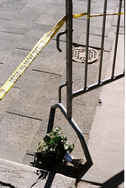 Flowers on ground near yellow police gate and tape.
