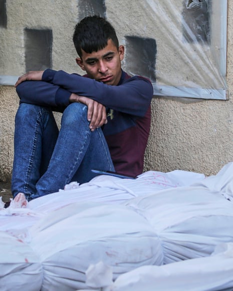 A young mourner sits next to the wrapped bodies of those killed overnight by an Israeli airstrike.