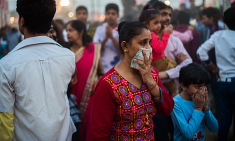 An Indian woman and a child cover their faces in an effort not to breath the fumes from fireworks and heavy dust