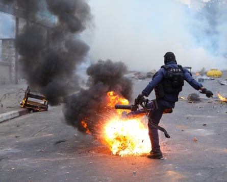 Debris, flames and police officer in protective geatr