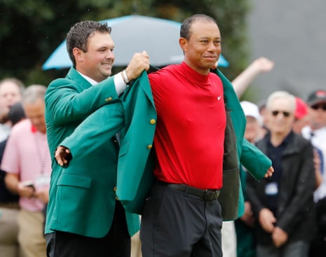 Reed helps Woods into his fifth green jacket.