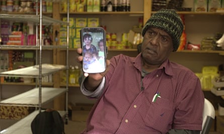 Abdishakur Mohamed Noor shows a photo of children on his cellphone. He hopes they can join him in the US one day.
