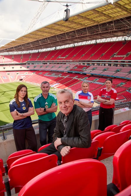 The group pose for the camera in a high stand at Wembley, with a view of the pitch behind them