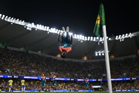 Nestory Irankunda does a back flip near the corner flag with the stadium and other players in the background