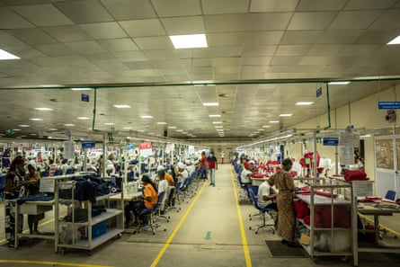 A shot of people at work in cotton factory, hunched over workstations amid machinery