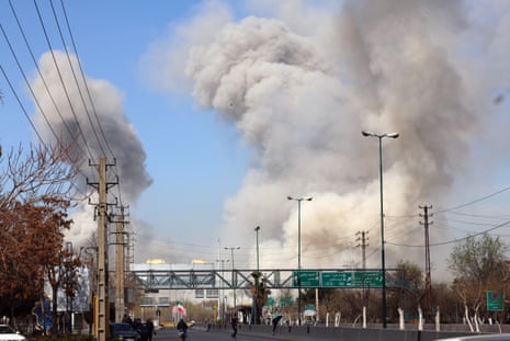 People run for safety after an airstrike in central Tehran, as smoke rises near a major road.
