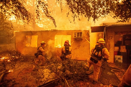 Firefighters push down a wall while battling against a burning apartment complex in Paradise, north of Sacramento, California on 9 November 2018.