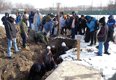 people stand near and in a grave
