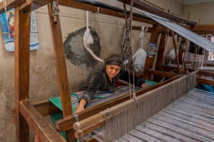 A woman works a large floor loom.