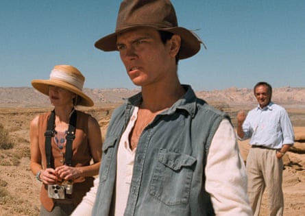A boy in a cowboy hat, a woman in a wide-brimmed hat, and a man in a blue shirt and chinos in the desert