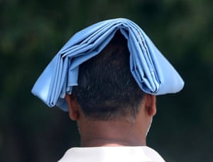A pedestrian covers his head  in Delhi, India