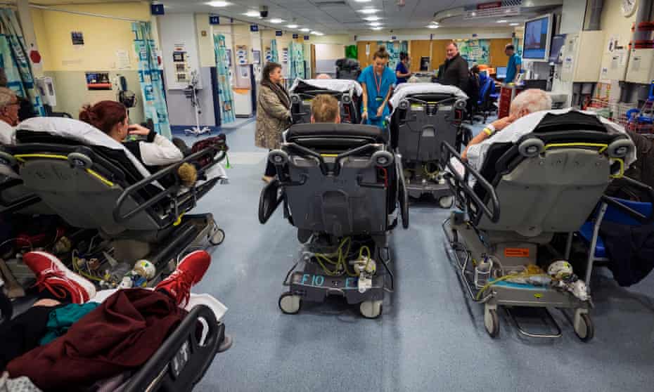 Patients on trolleys wait for attention at an NHS A&E department.