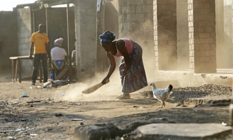 A woman sweeps outside her house in Lusaka, Zambia,