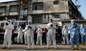 Workers wearing protective suits pray before a disinfection operation in Kuala Lumpur