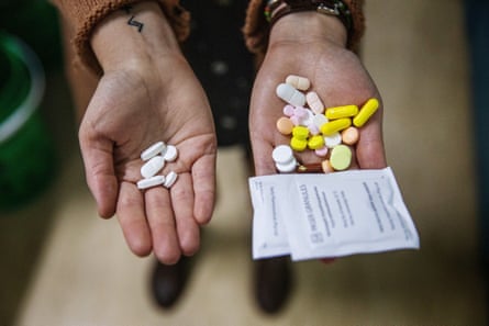 A pharmacist holds two sets of pills in her hands, showing the difference between the amount of tablets a patient takes on the new TB treatment versus the old. 
