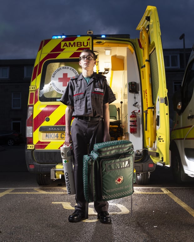 Calum Leitch, who had a place to read medicine, but after volunteering with the Red Cross has decided to become a paramedic, standing by the back of an ambulance holding a medical bag and an oxygen cylinder