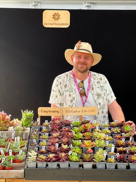 Drewitt smiling behind tray of small potted plants