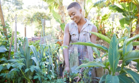A young woman working in her abundant garden.