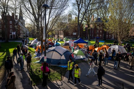 people walk past tents on a university campus