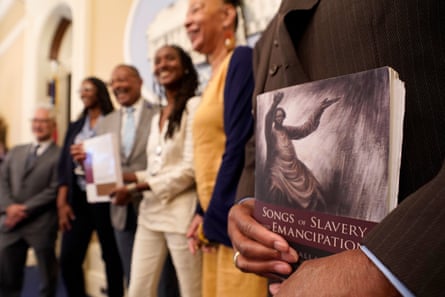 man holds book in foreground as others smile in background