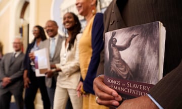 Men and women stand in a line and smile, with one holding a book called Songs on Slavery and Emancipation