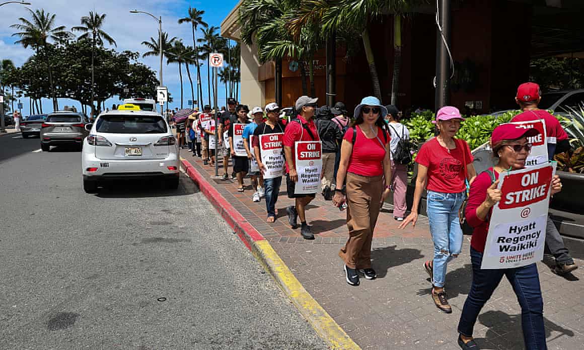Hotel workers wearing red shirts and carrying signs reading