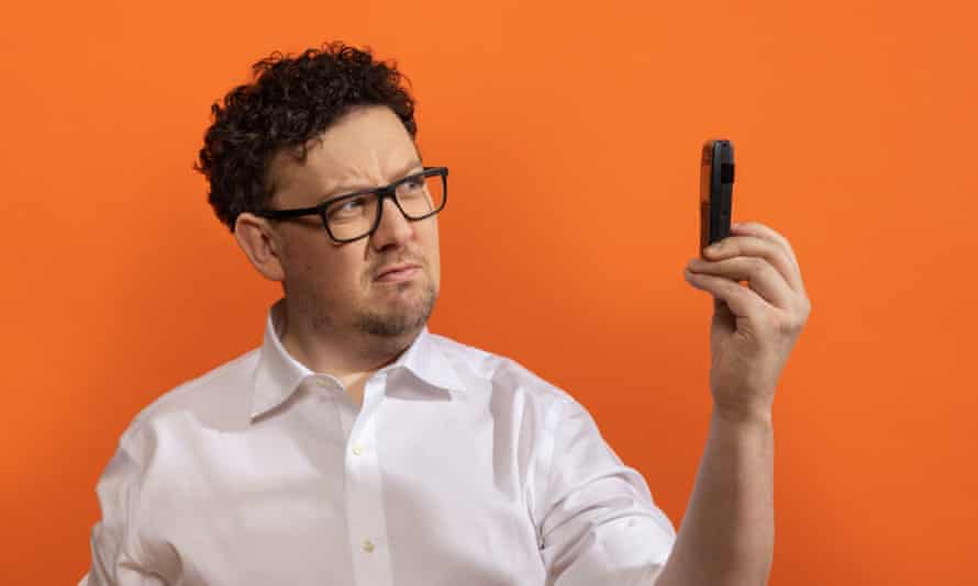 James Ball holding up a Nokia mobile phone against an orange background