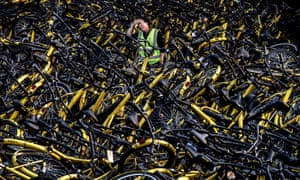 A mechanic from bike share company Ofo stands amongst damaged bicycles needing repair in Beijing.