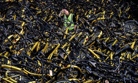 A mechanic from the bike-share company Ofo Inc stands in a Beijing repair depot among thousands of damaged bicycles that were pulled off the streets