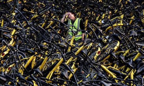 A mechanic from bike share company Ofo amongst a pile of damaged bicycles in Beijing.