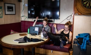 Two crew members below deck on soft seating repairing clothes