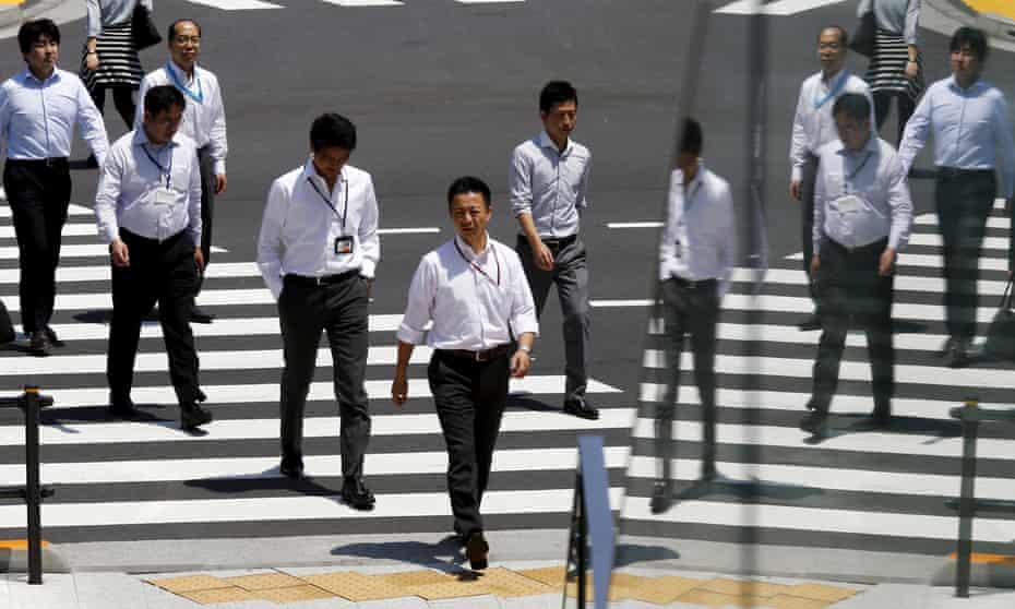Office workers cross a street during lunch hour in Tokyo