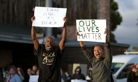 An image of protestors holding placards that read 'Every One in Black' and 'Our Lives Matter'