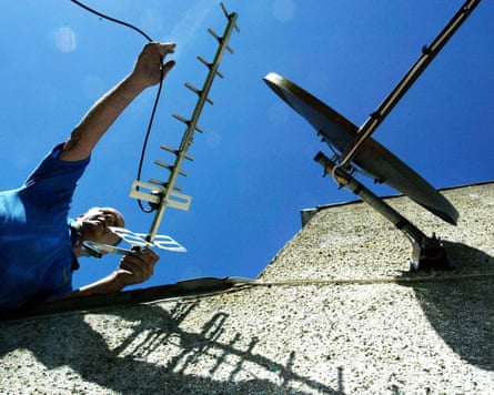 A technician takes down a TV aerial from a roof
