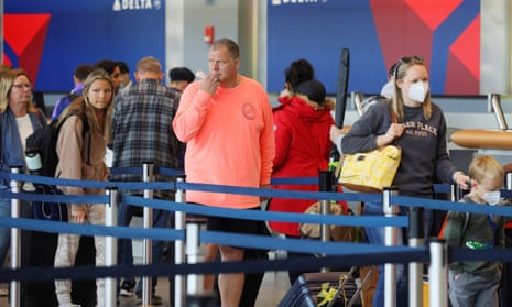 Travellers wearing masks and not wearing masks wait in line at a Delta Airlines counter at Logan international airport in Boston this week.