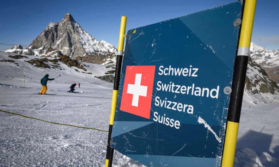 Skiers hit the slopes past a banner showing Swiss border