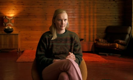 A woman with blond hair sitting in a room with red lighting behind her