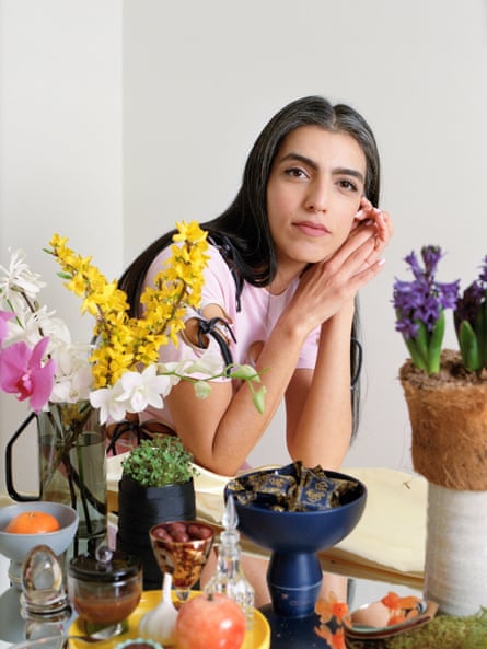 A woman poses with floral arrangements on a table in front of her