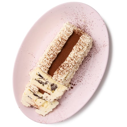 Felicity Cloake’s Viennetta. sprinkled with cocoa powder. A sliced Viennetta with wavy layers and chocolate pieces, dusted with cocoa powder on a pink plate.