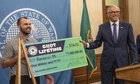 Kameron M, 23, with Washington state governor Jay Inslee, right, after accepting a mock check for $1m, which he won as part of the state’s ‘Shot of a Lifetime’ lottery, open to all who got the Covid-19 vaccine. The motorcycle mechanic didn’t know about the lottery and said he got his vaccine as soon as he could because he thought it was the right thing to do.