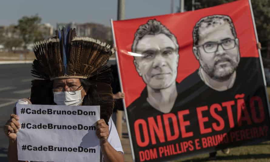 A man stands next to a poster of Dom Phillips and Bruno Pereira, who went missing in the Amazon a week ago.