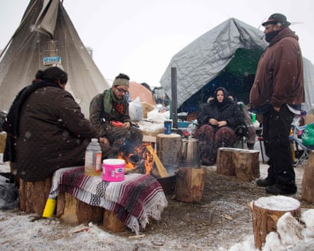Activists sit around a campfire as it snows on the edge of the Standing Rock Sioux Reservation in December 2016. TSON/AFP/Getty Images
