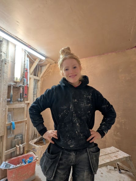 Hannah Spencer in dark workwear in a plastered room with a partly exposed timber wall visible